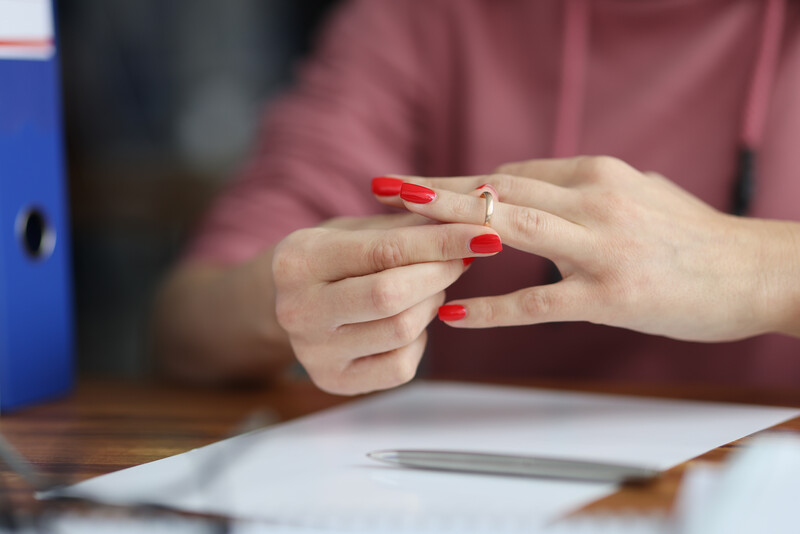Family law: A recently divorced or seperated woman removing her wedding ring after signing divorce papers