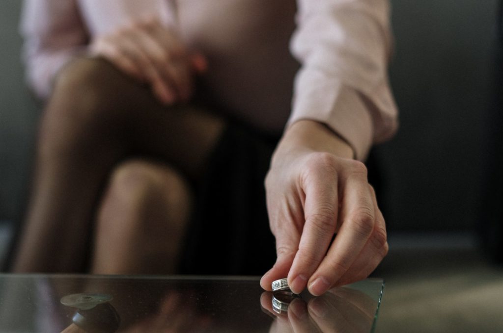 A woman placing her wedding ring on a glass desk having been divorced